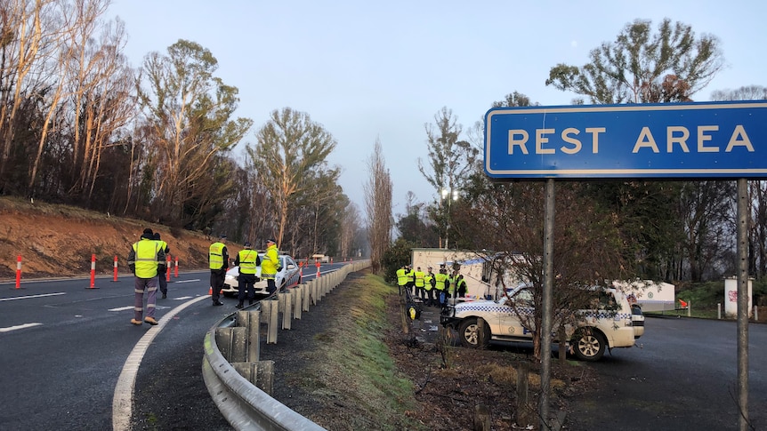 Police officers stand on a road, at a border checkpoint.