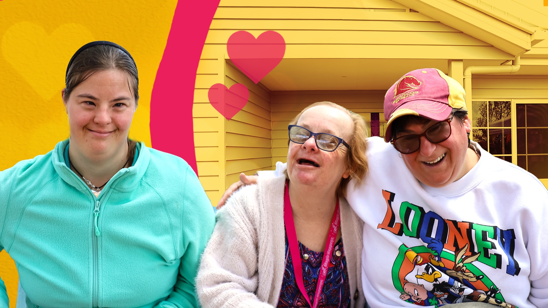 Three women smile with joy in front of a brand new house.