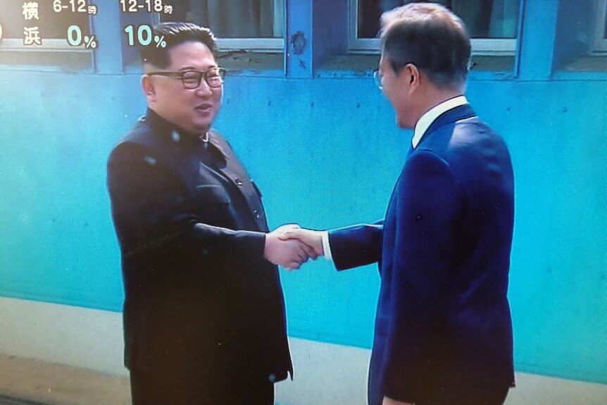 Two men shake hands.