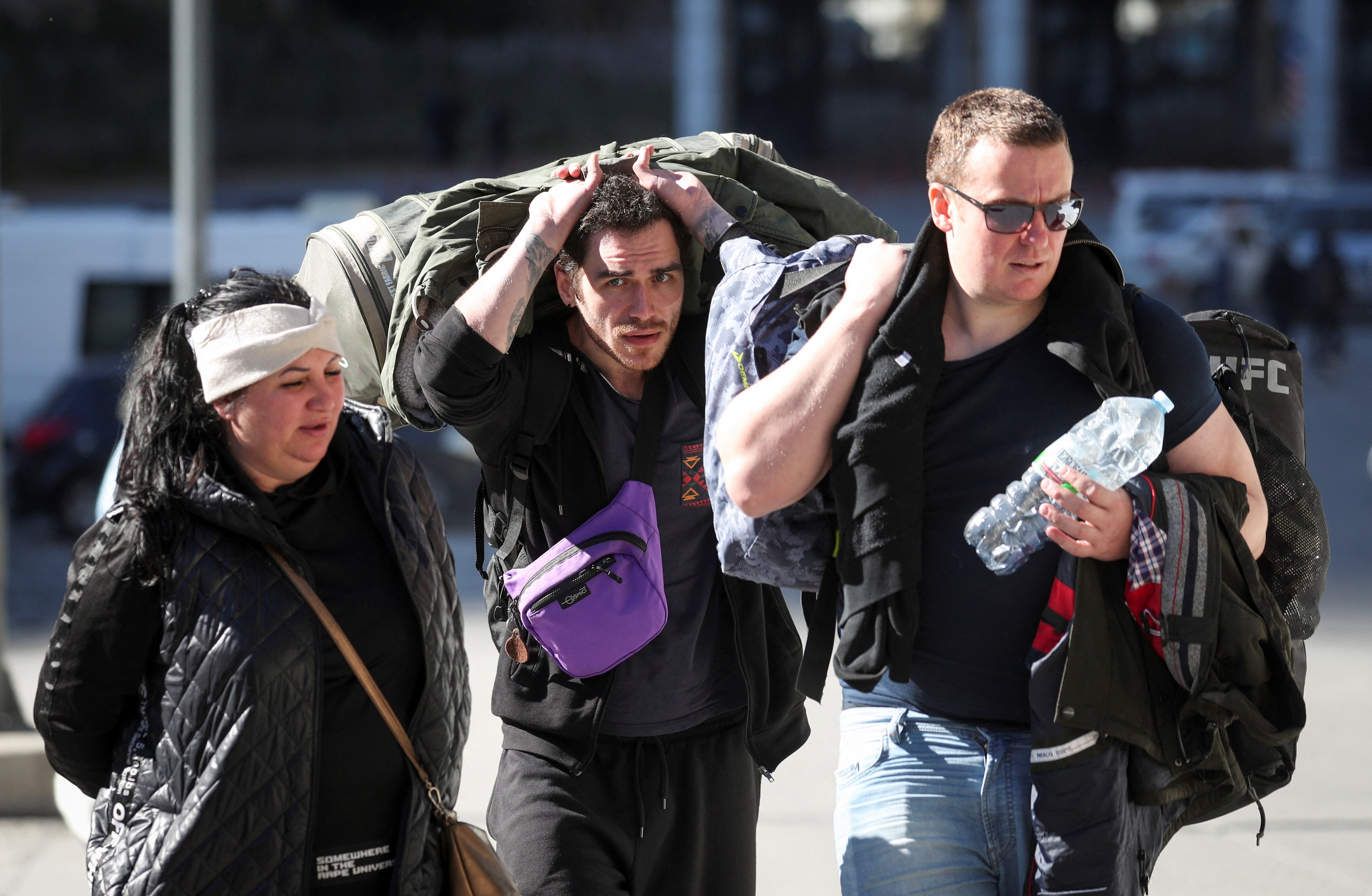 three people carry bags and suitcases across the russian border 