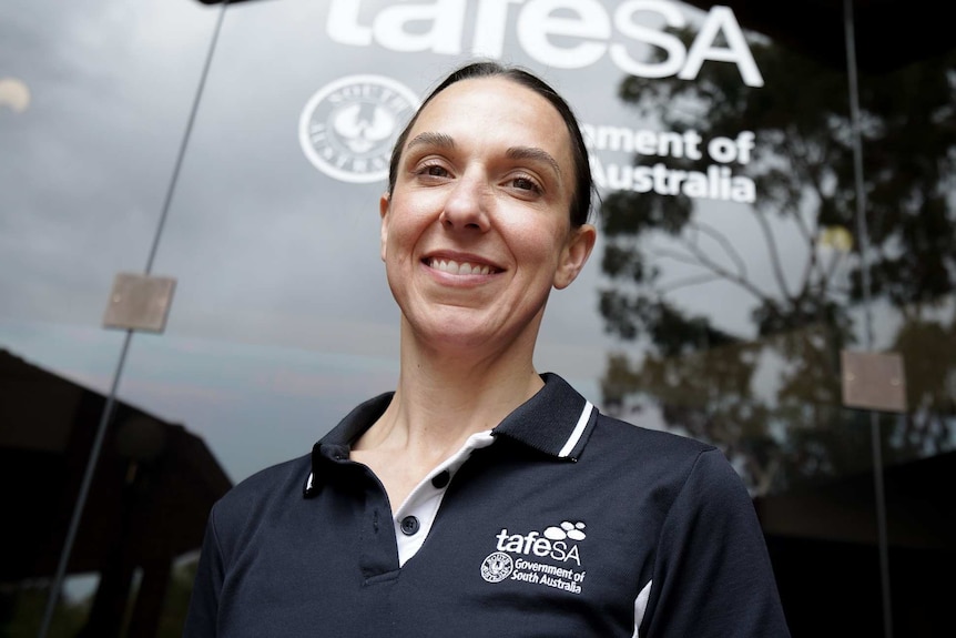 A woman standing in front of a window with the words tafeSA on it