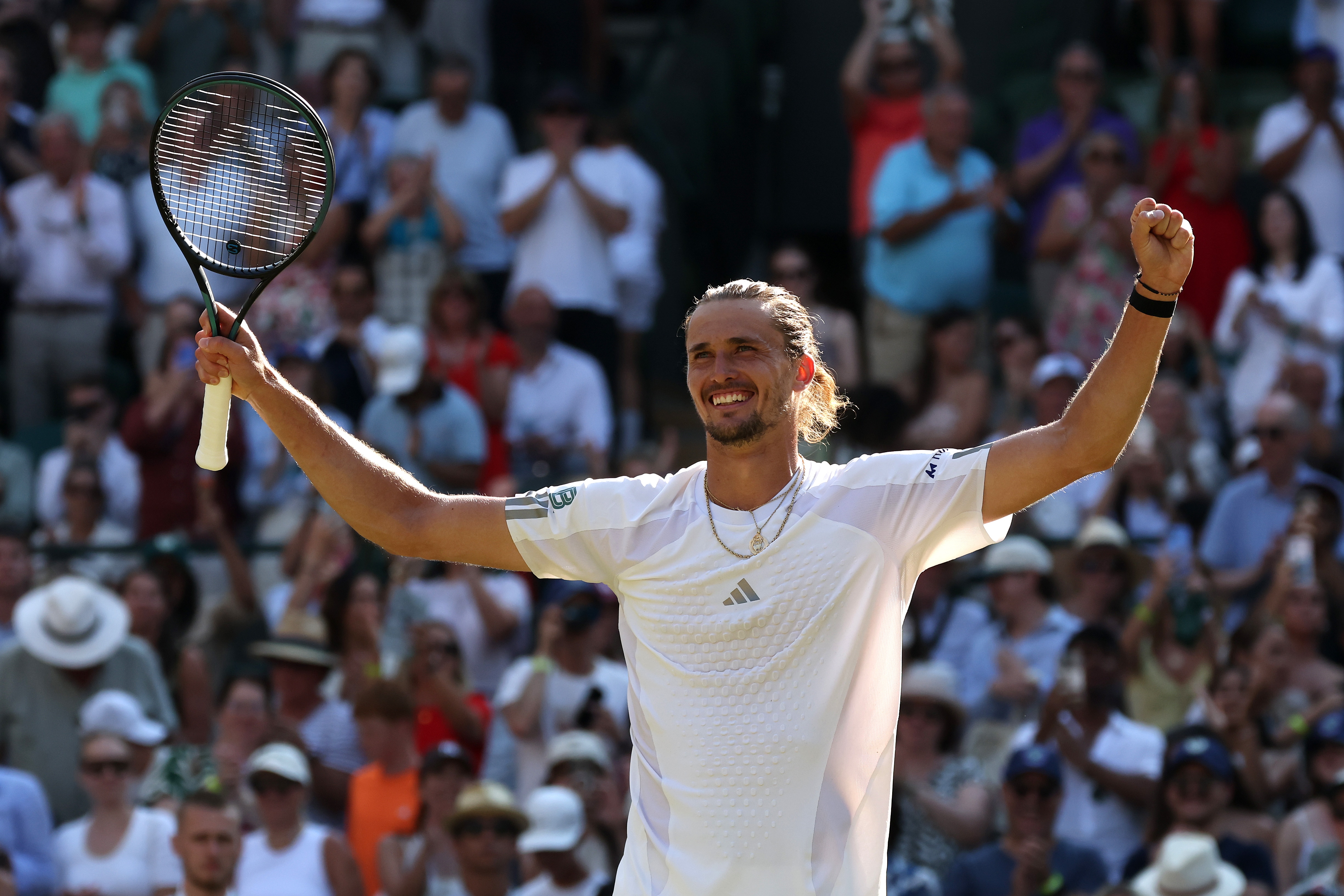 Alexander Zverev raises his arms in celebration holding racquet.