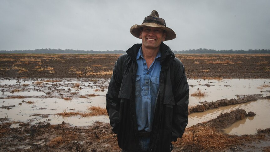 Farmer Guy Shoemark stands in rain in front of flooded cotton paddock