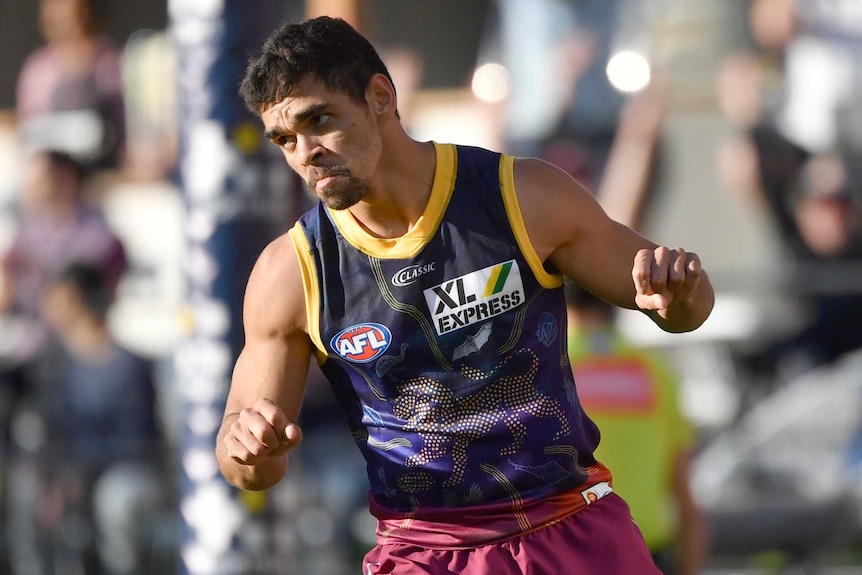 A Brisbane Lions AFL player moves both his hands as he celebrates kicking a goal against St Kilda.