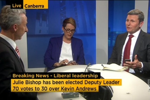 One woman and two men on air sitting at TV news desk.