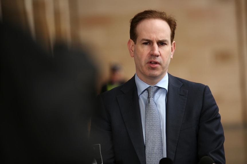 A man in a suit and tie speaking to media