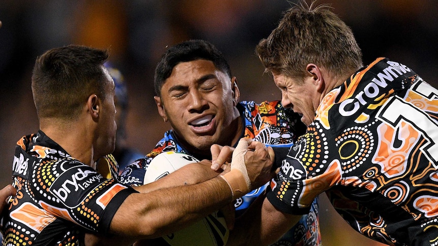 Jason Taumalolo is tackled by Luke Brooks and Chris Lawrence.