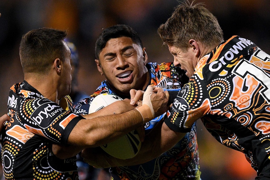 Jason Taumalolo is tackled by Luke Brooks and Chris Lawrence.