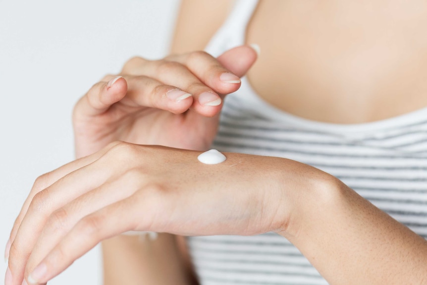 Woman rubs cream into the back of her hand