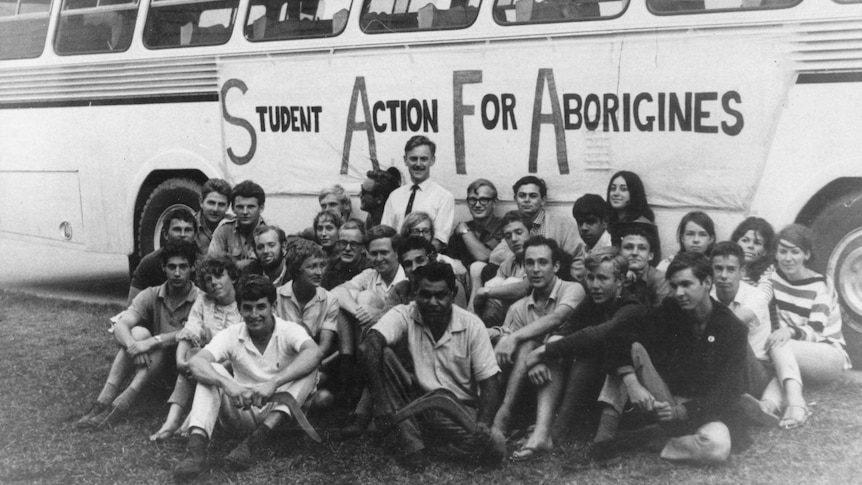 The freedom riders sit in a group in front of their bus in 1965