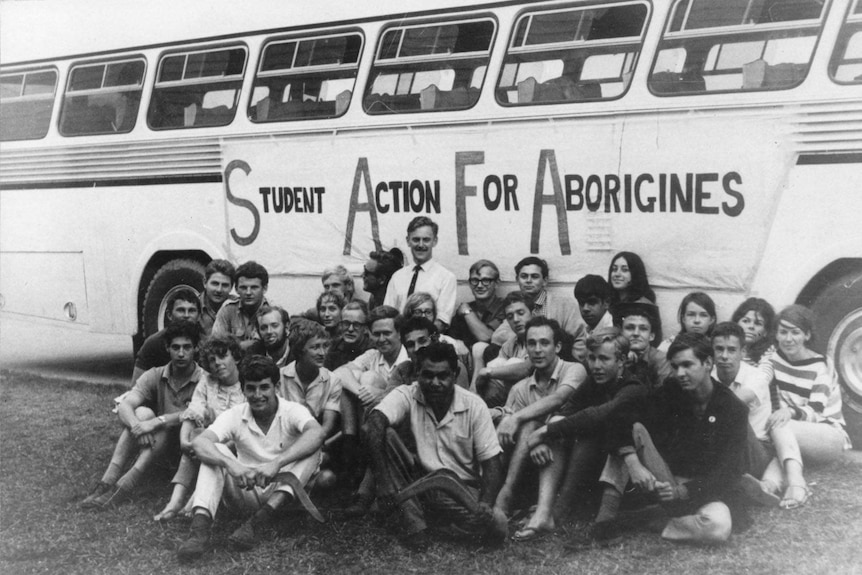 The freedom riders sit in a group in front of their bus in 1965