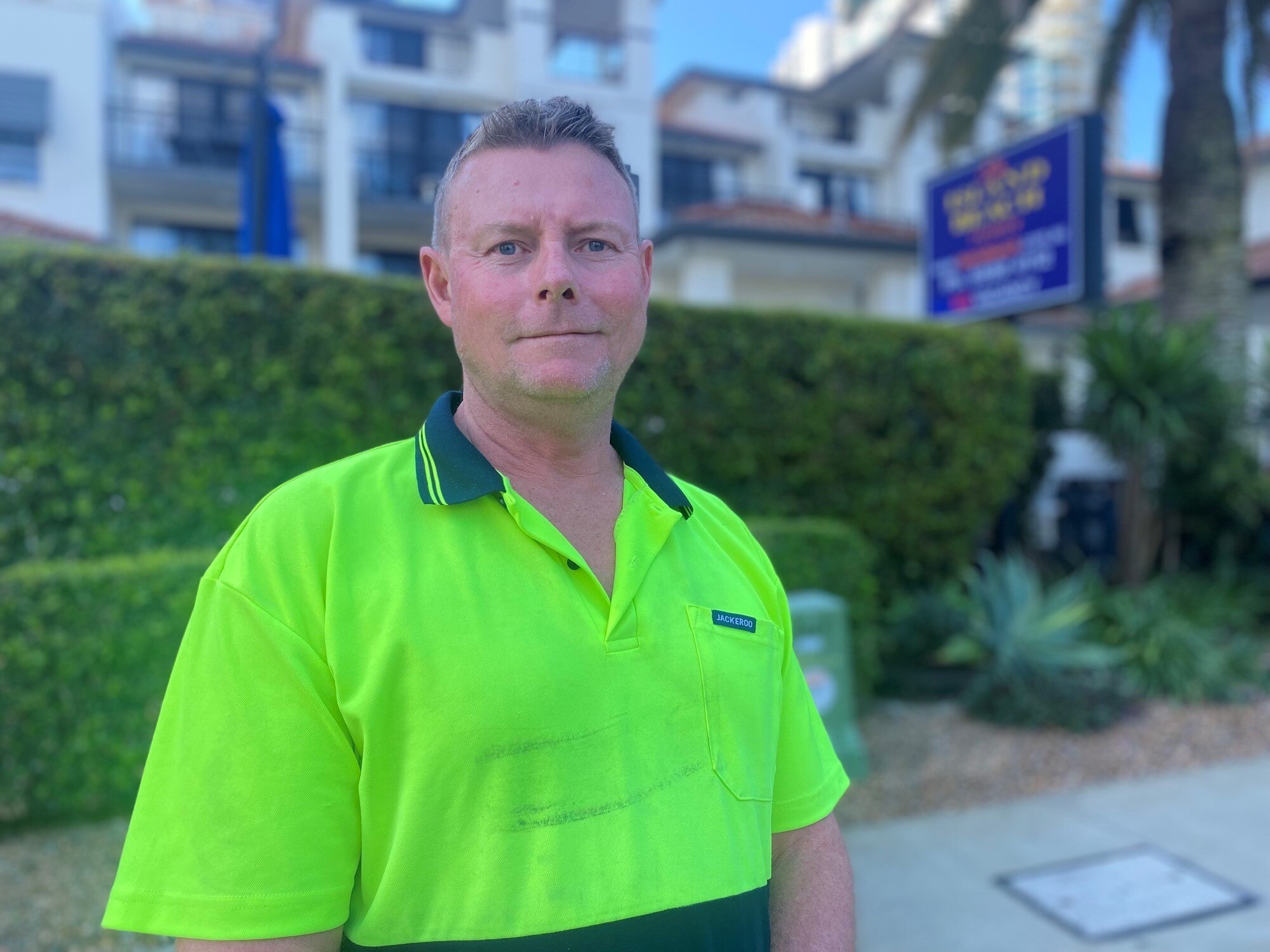 Man in high visibility yellow shirt standing in front of building
