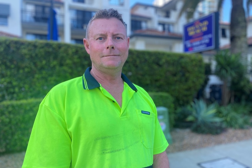 Man in high visibility yellow shirt standing in front of building