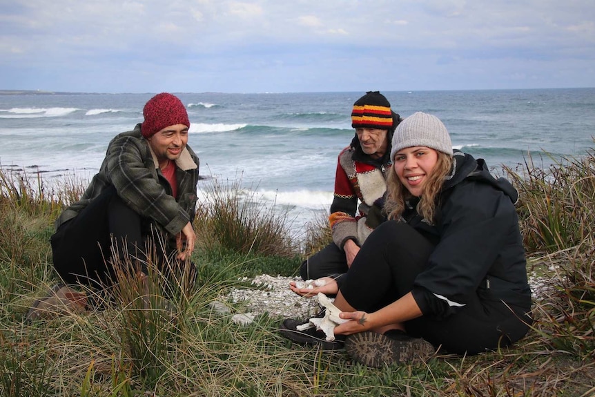 Three people at an Aboriginal shell midden on a beach.