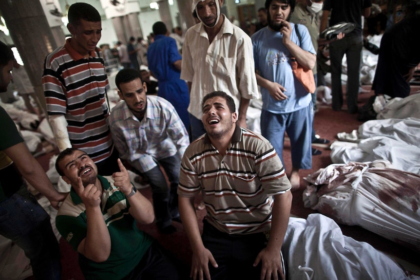 Egyptians mourn next to of bodies wrapped in shrouds at a mosque in Cairo.