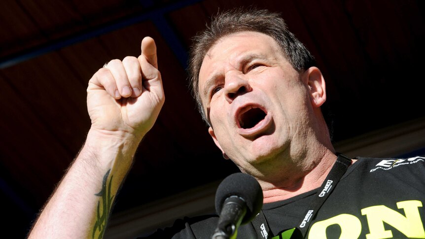 CFMEU secretary John Setka waves his fist in the air as building and construction workers march during a rally in Melbourne.