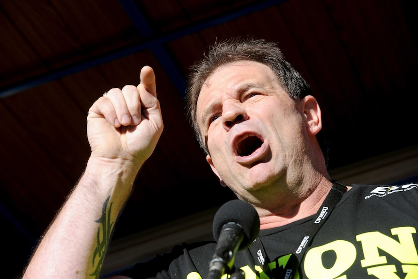 CFMEU secretary John Setka waves his fist in the air as building and construction workers march during a rally in Melbourne.