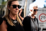 A woman named Fiona Bain walks along wearing dark sunglasses.