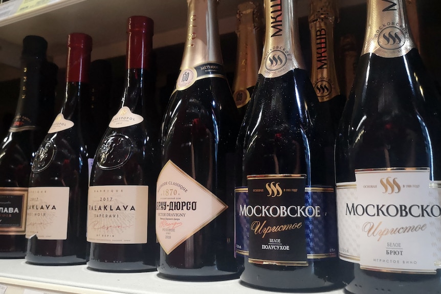 Sparkling wine bottles with Russian labelling on a shelf.