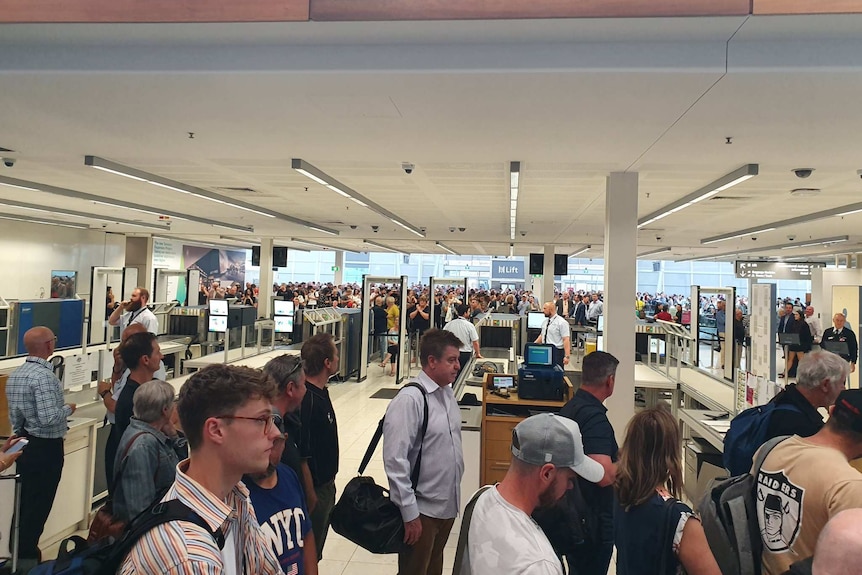 Passengers standing in lines evacuate Adelaide Airport.