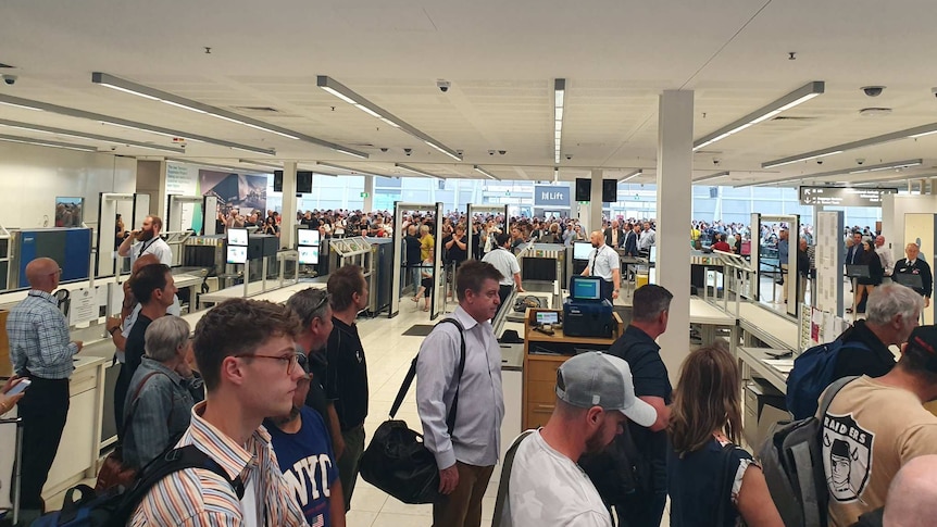 Passengers standing in lines evacuate Adelaide Airport.