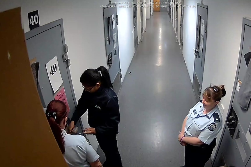 Une image fixe de CCTV montre des agents pénitentiaires debout devant une porte de prison verrouillée.