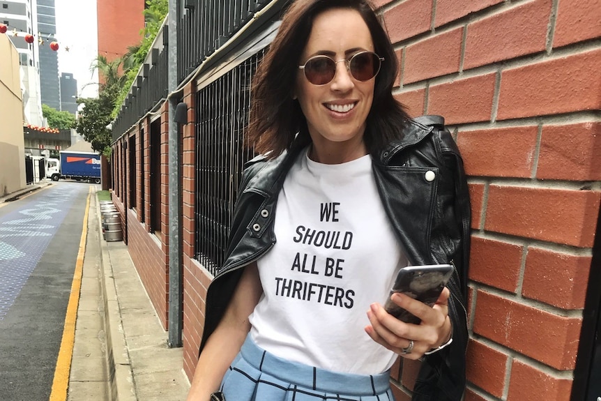 Woman leaning against wall holding phone