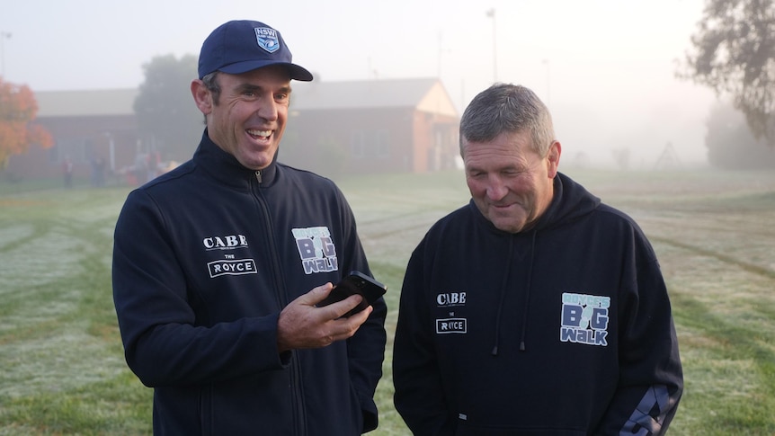 Two men in jumpers standing in a field 