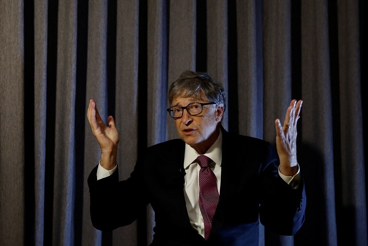 A man in a suit holds his hands up as he speaks to a crowd.