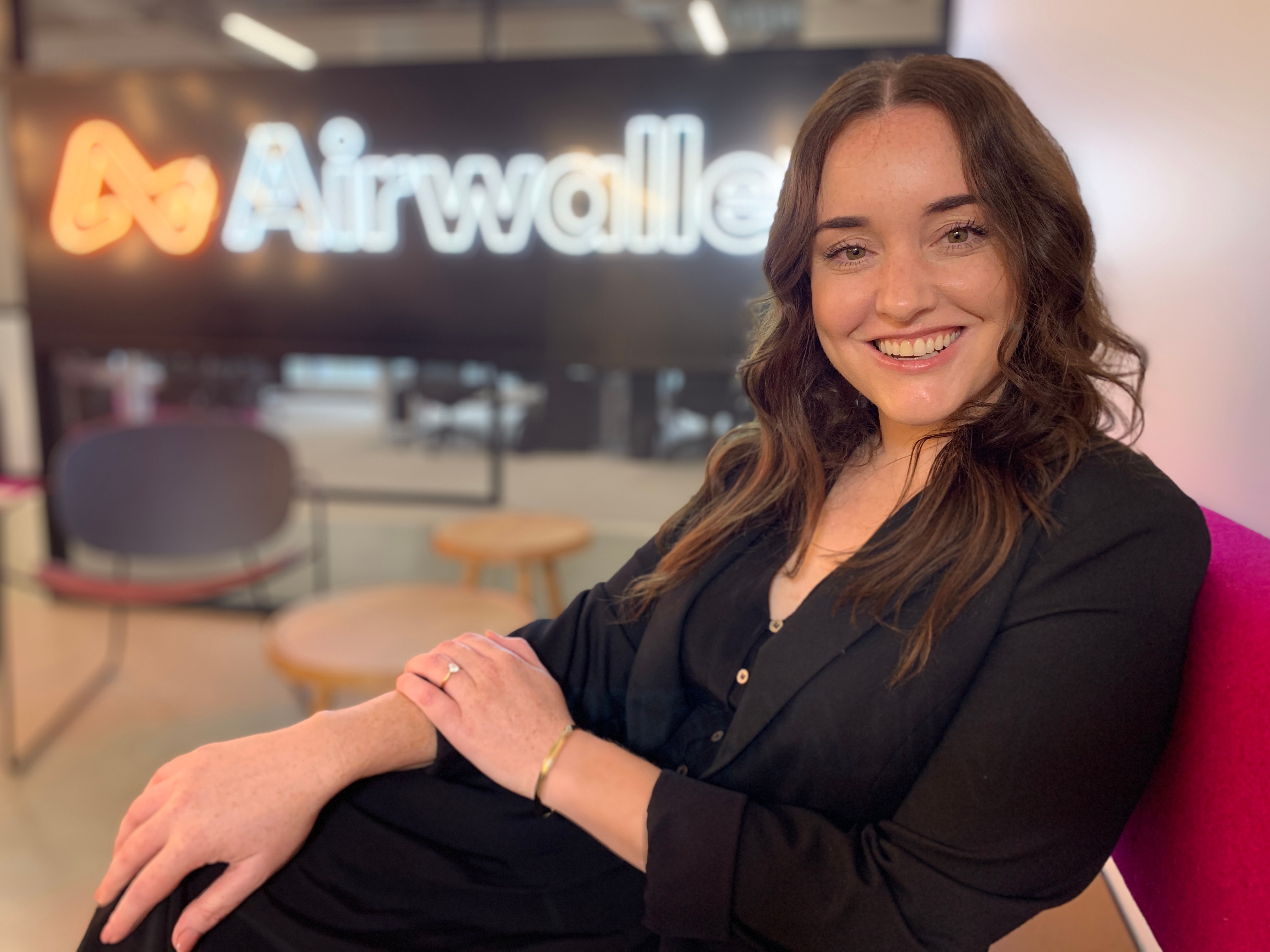 Emily Mason sits in an office with an AirWallex sign behind.