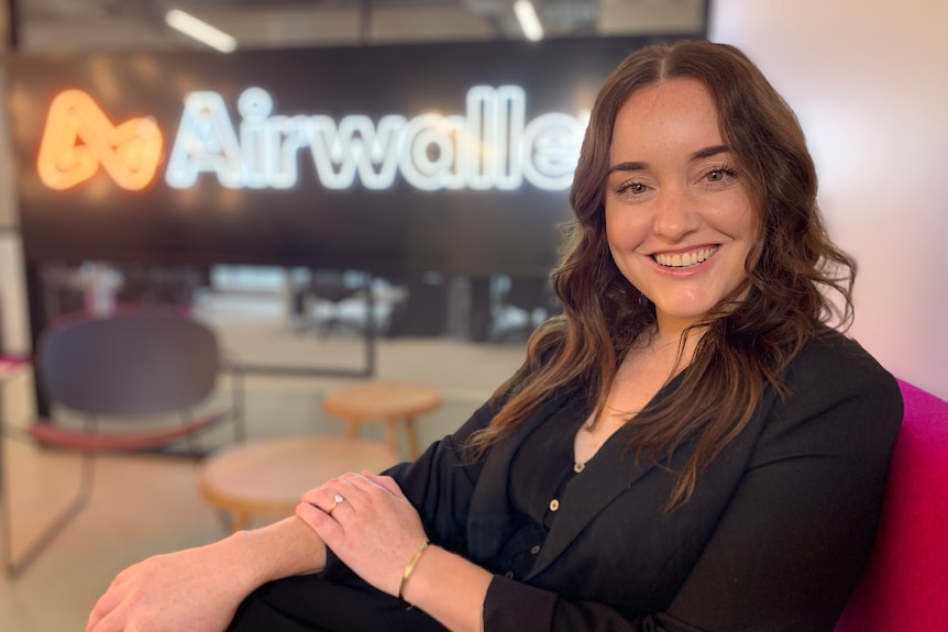 Emily Mason sits in an office with an AirWallex sign behind.