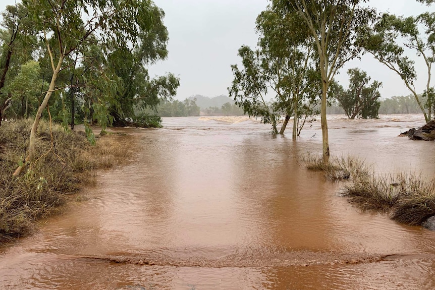 A road leading to a river weir, which is completely flooded.