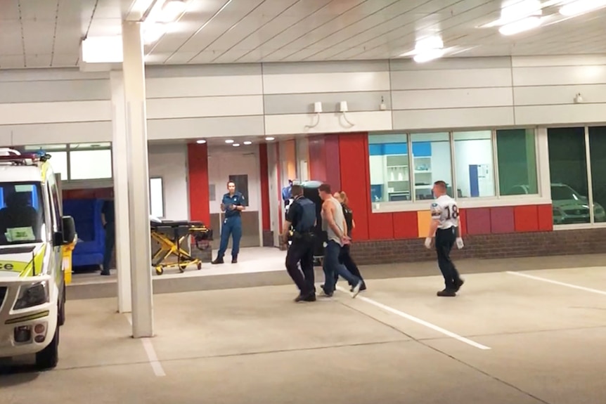Police escorting the man into Mackay hospital