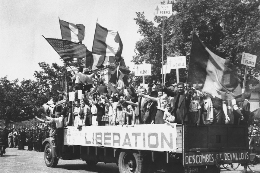 Truck full of Parisians waving flags and carrying Vive De Gaulle banners drives through the city.