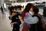 A family hug at the departure area of an airport.