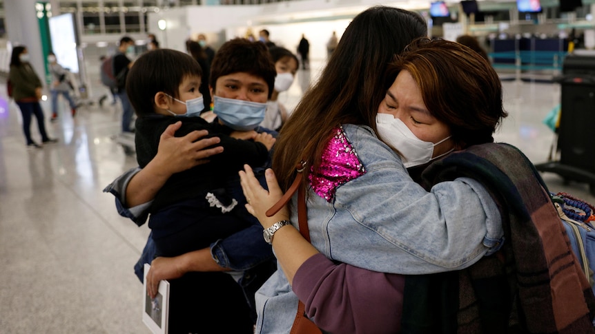 A family hug at the departure area of an airport.