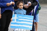 A young girl holding a handpainted flag of Greece