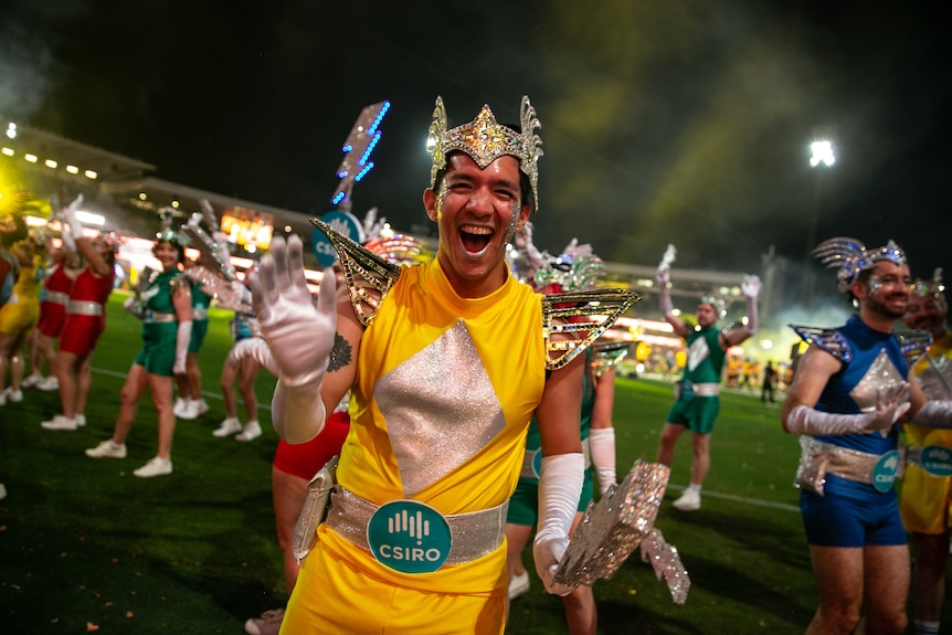 a  man smiling wearing a yellow outfit and silver headdress