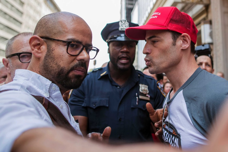 A NYPD officer separates two men arguing about trump