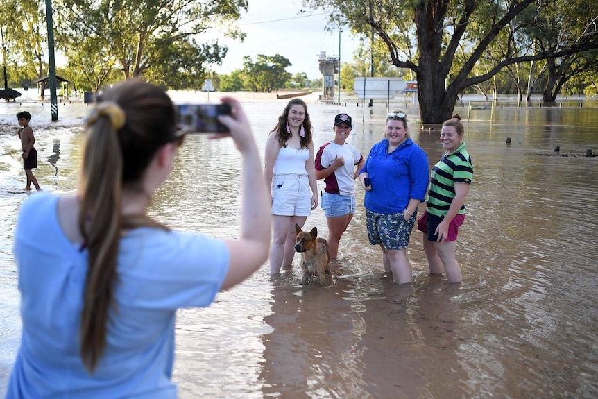 Locals pose for a photo in flood water in St George.