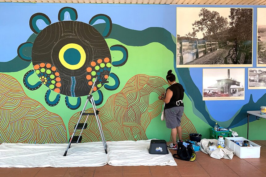 Aboriginal artist Tamara Murray paints on a mural