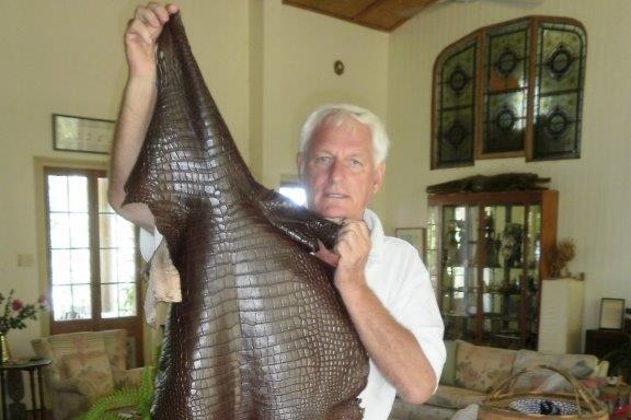 John Lever holds a dark brown crocodile skin almost as tall as him