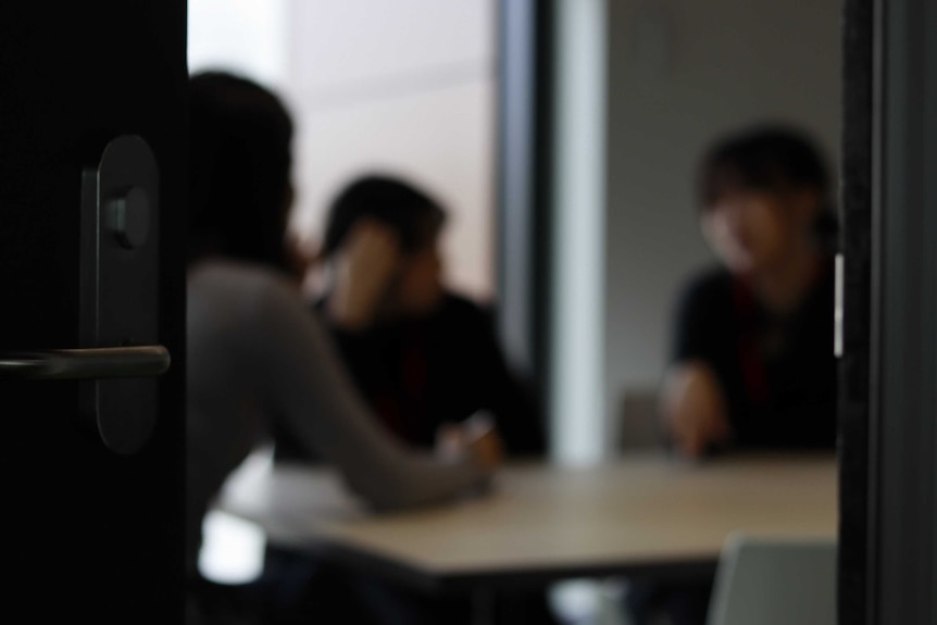 A blurred picture of three females sitting at a table in a room.