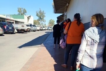 people in line waiting to enter the supermarket