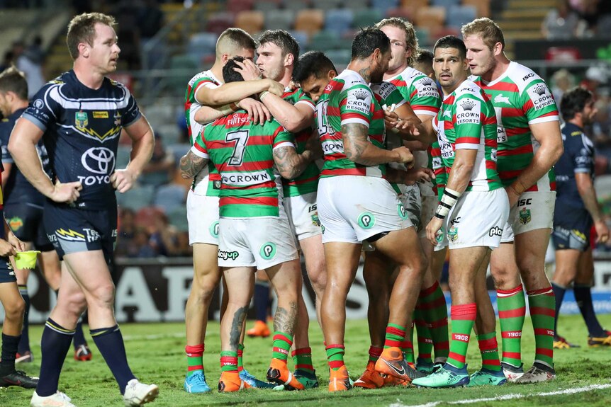 Michael Morgan of the Cowboys walks past a jubilant Rabbitohs side in Townsville.