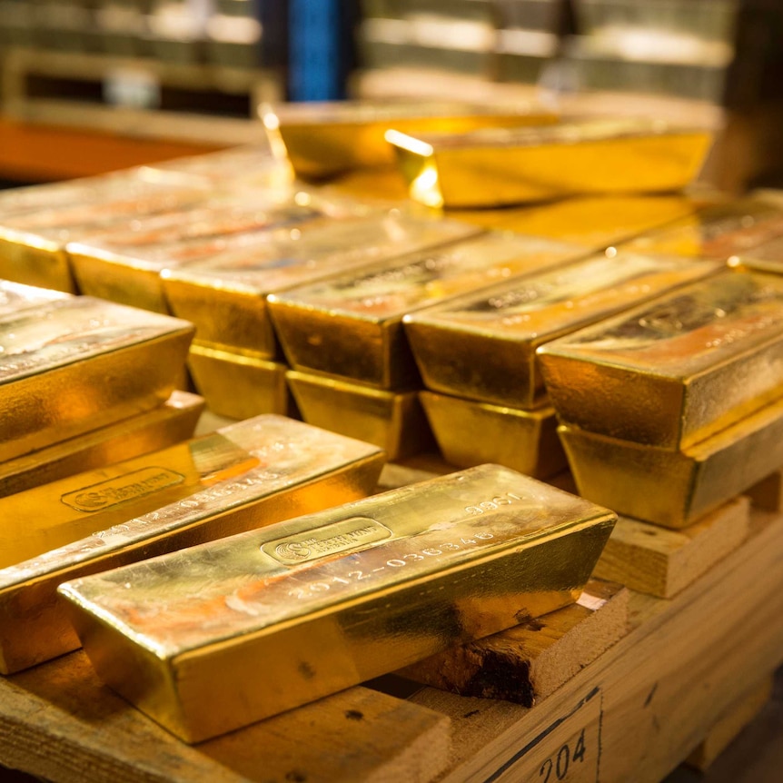 Gold bars piled on a wooden pallet.