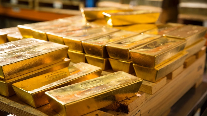 Gold bars piled on a wooden pallet.