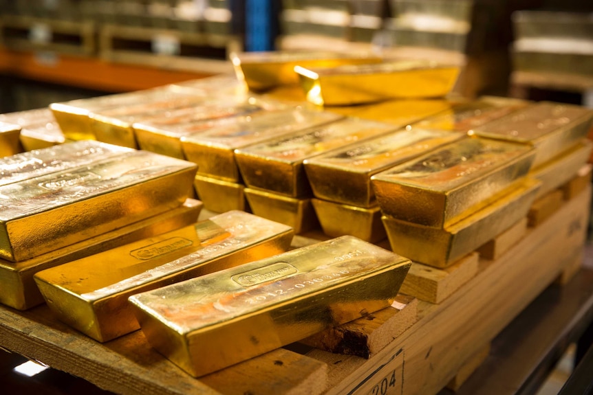 Gold bars piled on a wooden pallet.