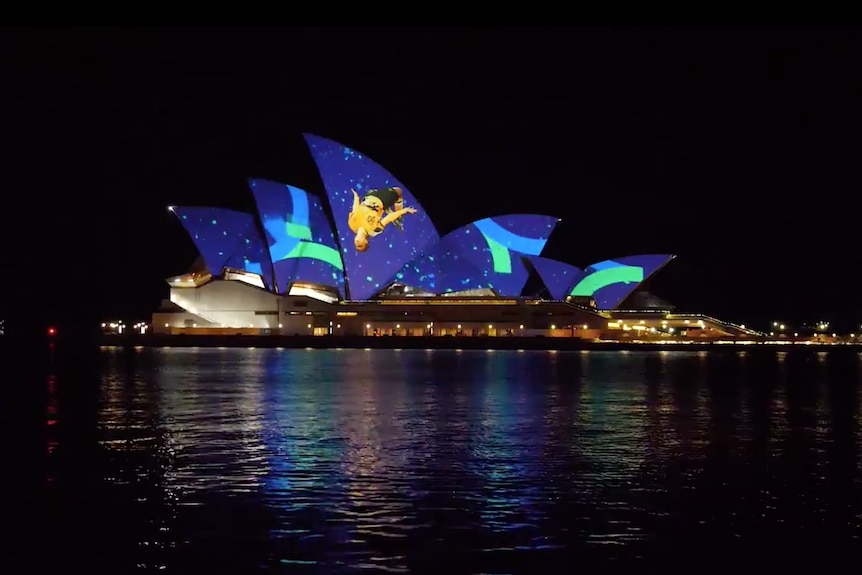 A projected image in the sydney opera house of blue and green confetti falling behind Sam Kerr mid-backflip