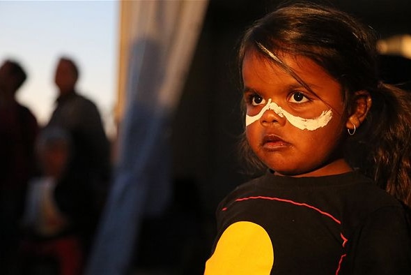 Indigenous girl with face paint and Aboriginal flag t-shirt in story about how to raise culturally aware kids.
